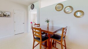 A dining area with a wooden table and chairs, a vase with flowers, and three decorative mirrors on the wall. - Palm Bay Cove | House in Palm Bay (Palm Bay)