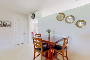 A dining area with a wooden table and chairs, a vase with flowers, and three decorative mirrors on the wall. - Palm Bay Cove | House in Palm Bay (Palm Bay)