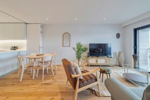 Ein modernes Wohnzimmer mit Essbereich, einer Couch, einem Fernseher und einem großen Fenster.