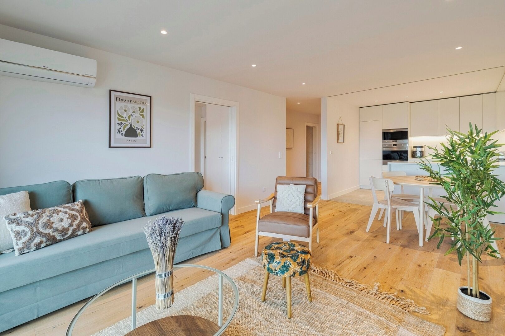 Een moderne woonkamer met een bank, een fauteuil, een bijzettafeltje en een potplant.