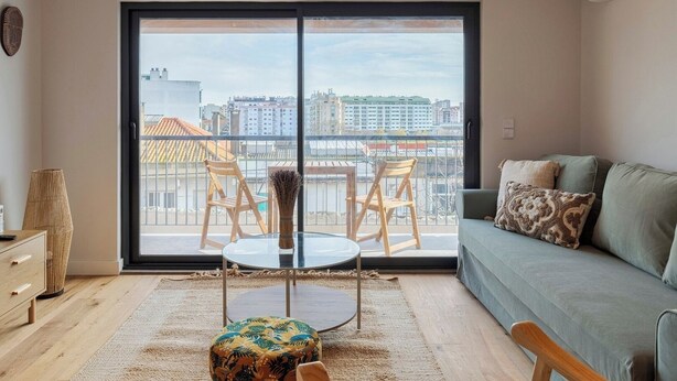 Een moderne woonkamer met een balkon, een bank, een tafel en stoelen.