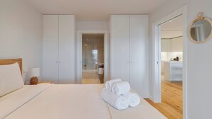 Een moderne slaapkamer met een groot bed, een bedlampje en netjes gevouwen handdoeken.