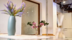 Ett kök med ett kylskåp, en vas med blommor och ett bord med en glasskiva.