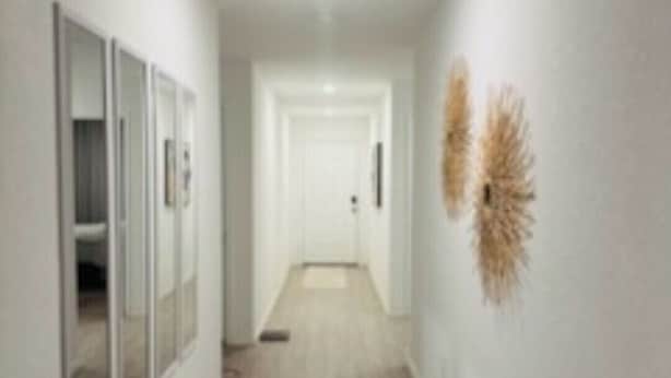 A hallway with a light-colored floor, white walls, and a door at the end. - Opossum Trail (New Braunfels)