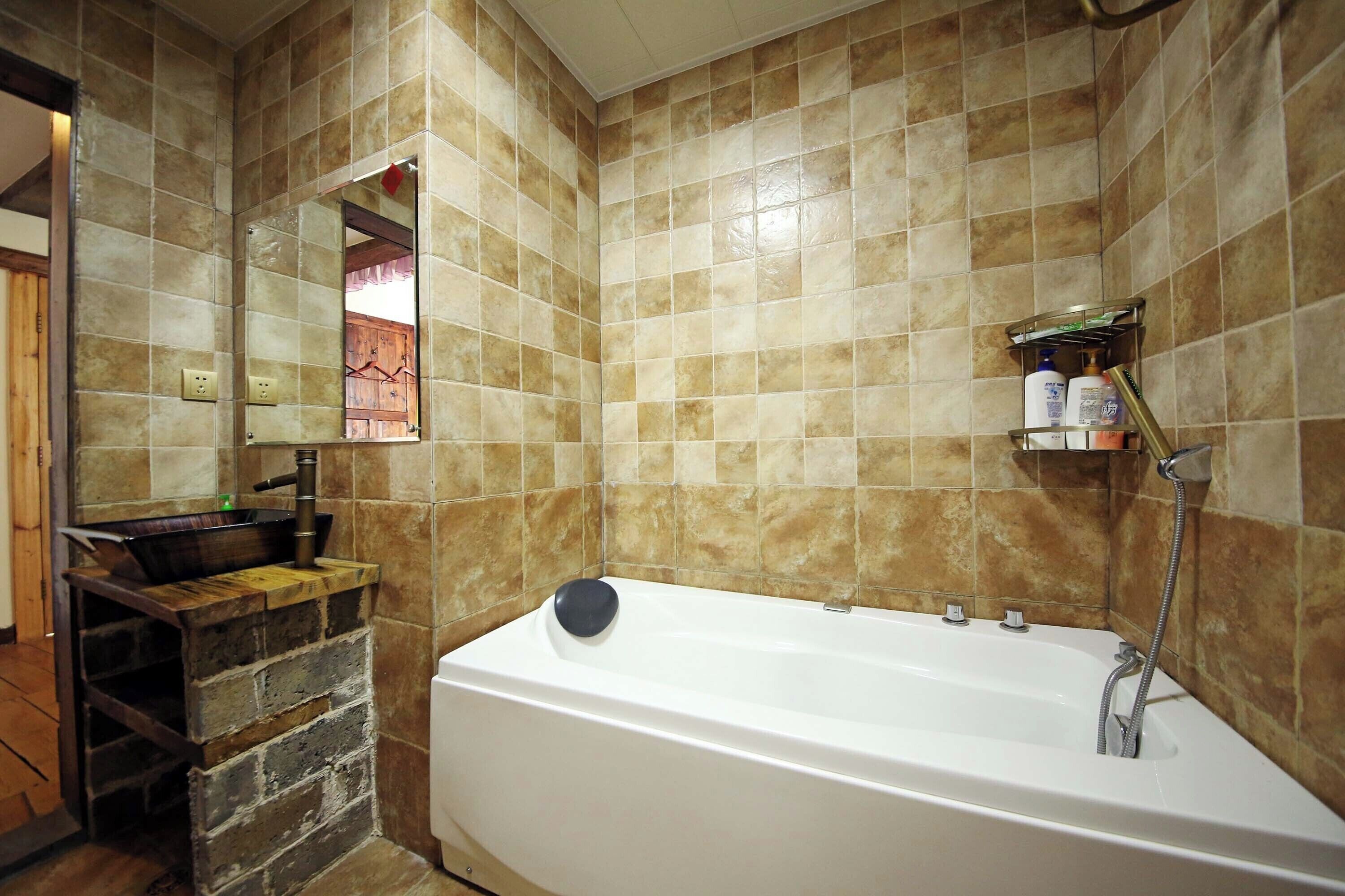 A bathroom with a bathtub, a wooden shelf with toiletries, and a mirror.