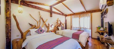 A rustic room with wooden beams, two beds with colorful bedding, a small table, and a window with curtains.
