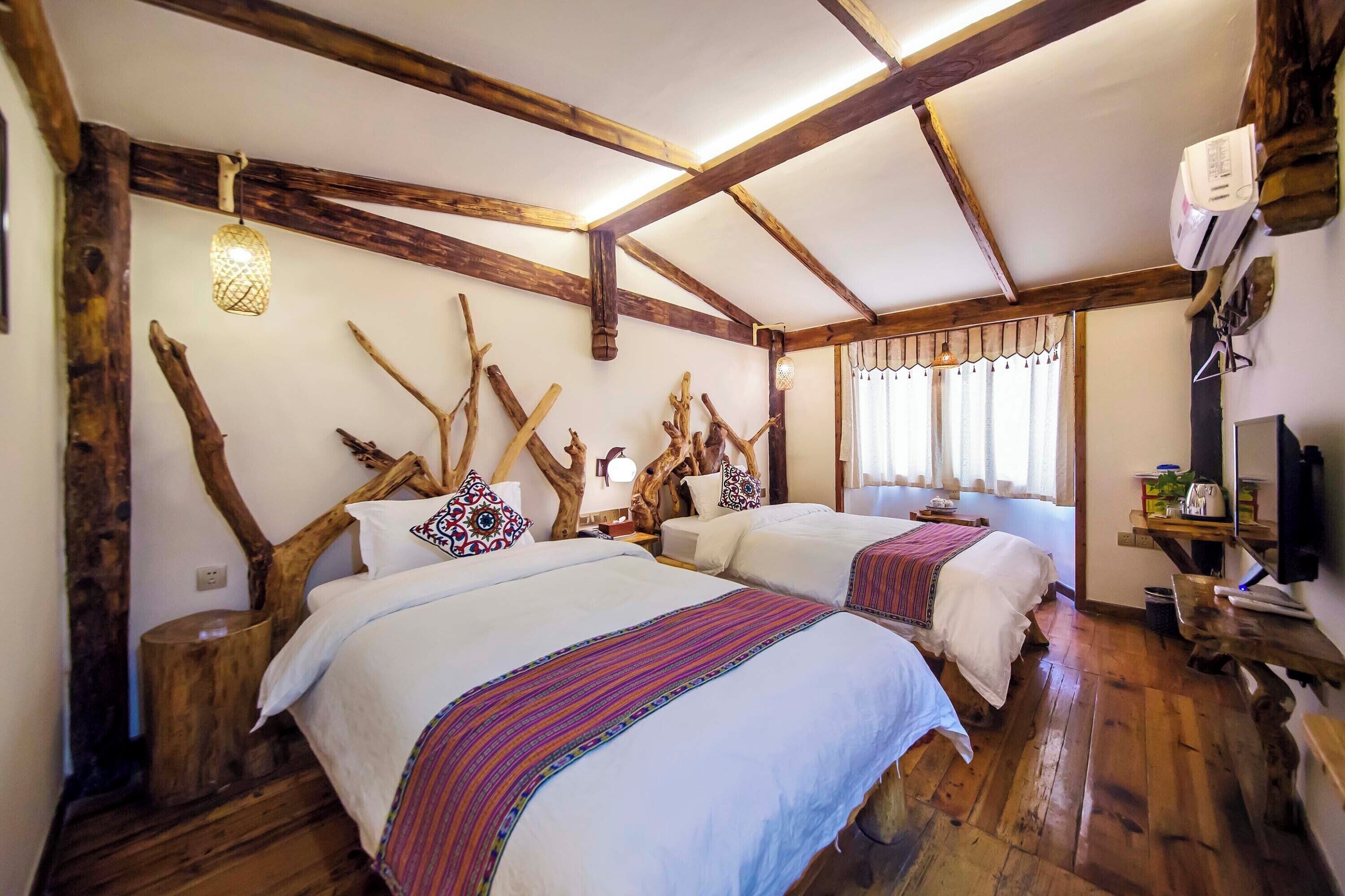 A rustic room with two beds, wooden beams, and a large window with curtains.