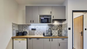 A compact kitchen with a microwave, kettle, and sink.
