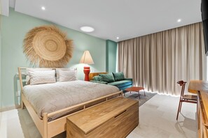 Ein modernes Schlafzimmer mit einem Holzbett, einem grünen Sofa, einem Holznachttisch und einem großen Fenster mit Vorhängen.