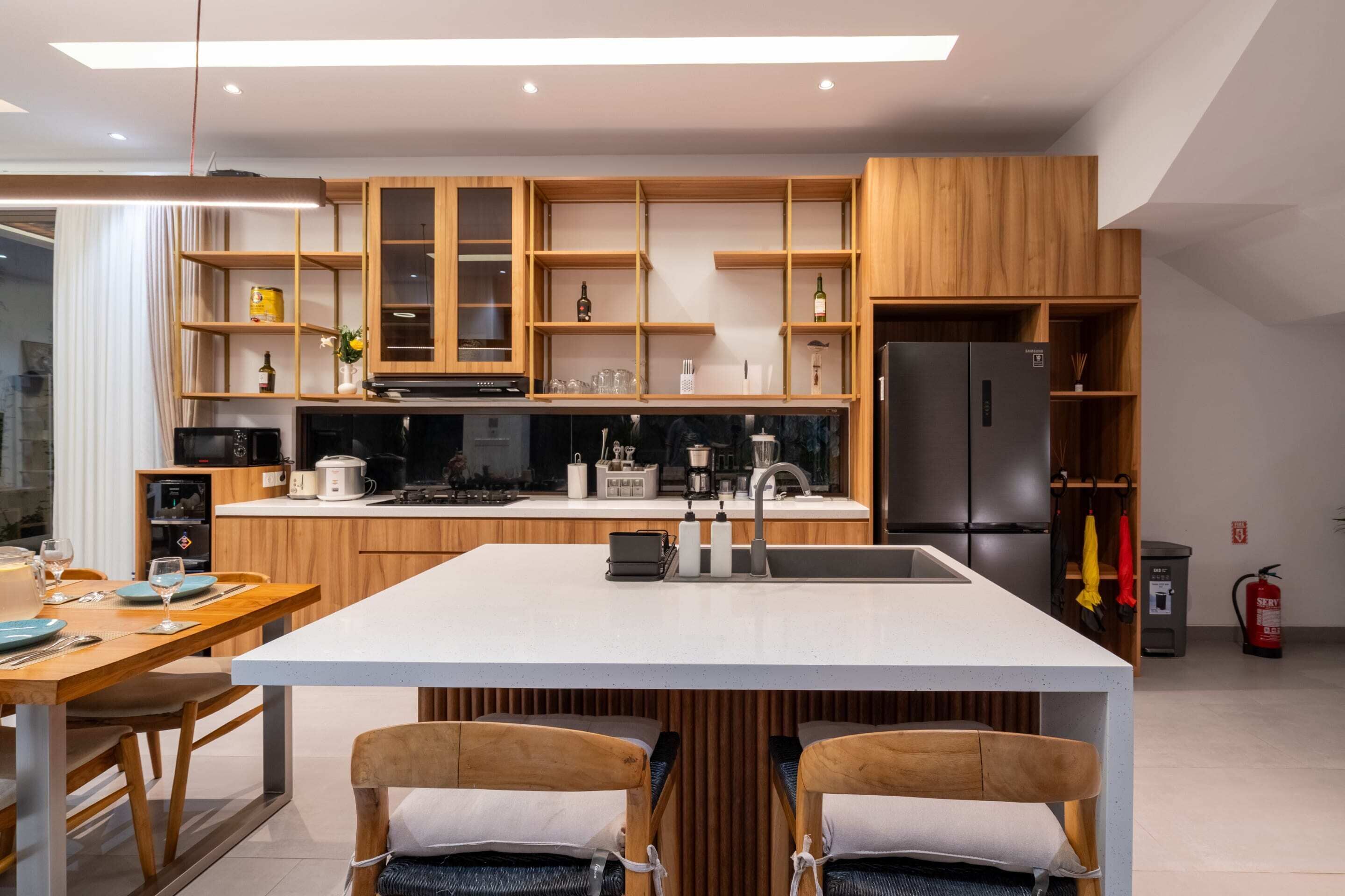 A modern kitchen with wooden cabinetry, a central island, and a dining area with two chairs.