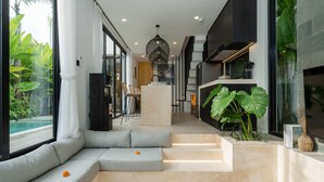 A modern interior with a seating area, a staircase, and a view of the outdoors. - Villa Sapta (Cemagi)