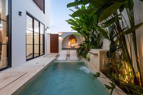 A modern pool area with a clear view of the pool, two lounge chairs, and a waterfall feature. - Villa Sevu 5 (Cemagi)