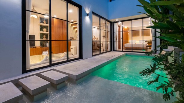 A modern indoor swimming pool with glass walls, a stone deck, and a view of the interior. - Villa Sevu 3 (Cemagi)