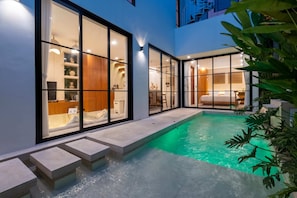 A modern indoor swimming pool with glass walls, a stone deck, and a view of the interior. - Villa Sevu 3 (Cemagi)