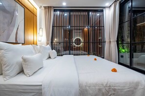 A modern hotel room with a large bed, white bedding, and a view through a window with curtains. - Villa Sevu 1 (Cemagi)