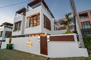A modern two-story building with a white facade, large windows, and a prominent logo on the front wall. - Villa Sevu 1 (Cemagi)
