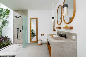 Une salle de bain moderne avec un lavabo en pierre, une douche en verre et un grand miroir.