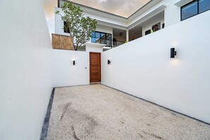 Un bâtiment moderne doté d’une cour intérieure, d’une porte en bois et d’un petit arbre.
