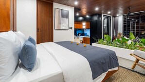 Ein modernes Schlafzimmer mit einem großen Bett, einem Deckenventilator und Blick auf eine Küche und einen Balkon.