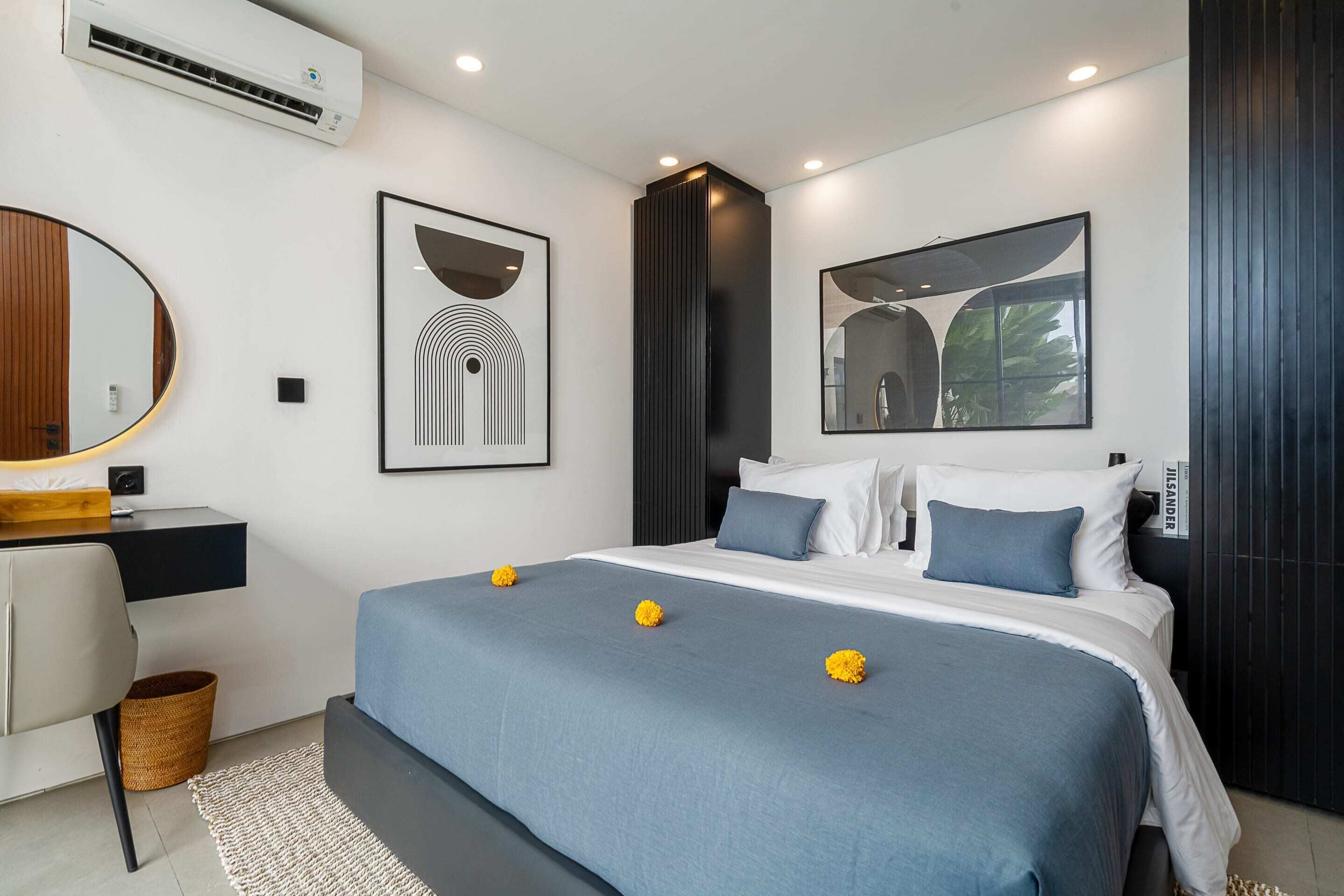 A modern bedroom with a large bed, a desk, and a mirror.