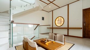 Un interno moderno con un tavolo da pranzo in legno, sedie imbottite, una scala in vetro e un muro in stile tradizionale con una finestra circolare.