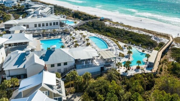 Un resort con diversi edifici, una vasta area piscina e una spiaggia.