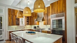Un'ampia cucina con una grande isola, mobili in legno e illuminazione a sospensione.