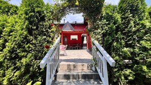 A staircase leading to a red building with a white railing, surrounded by lush greenery.