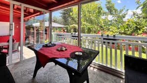 A covered patio with a glass door leading to a garden.