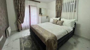 A bedroom with a bed, curtains, a mirror, and a radiator.
