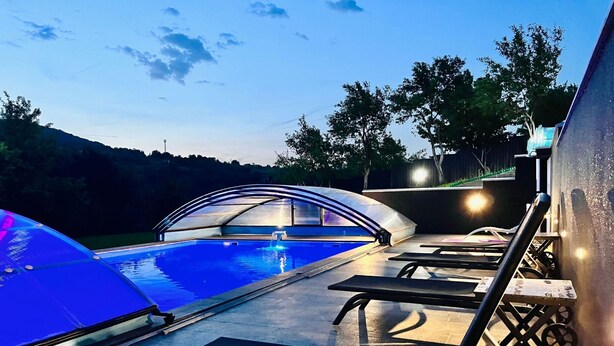 A pool area with lounge chairs and a covered seating area.