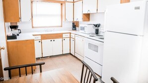 A kitchen with wooden cabinets, a white refrigerator, a stove, and a microwave.