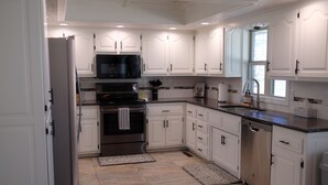 A modern kitchen with white cabinetry, stainless steel appliances, and a black countertop. - Comfortable Home Near CoxHealth & MSU - Fenced Yard (Springfield)