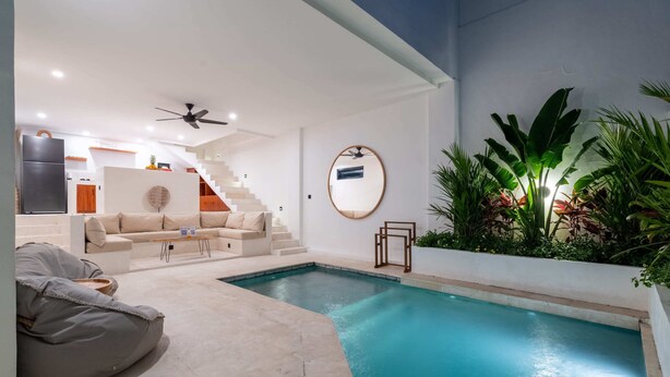 A modern indoor pool area with a staircase, a sofa, and a bean bag chair. - Villa Ombak (Cemagi)
