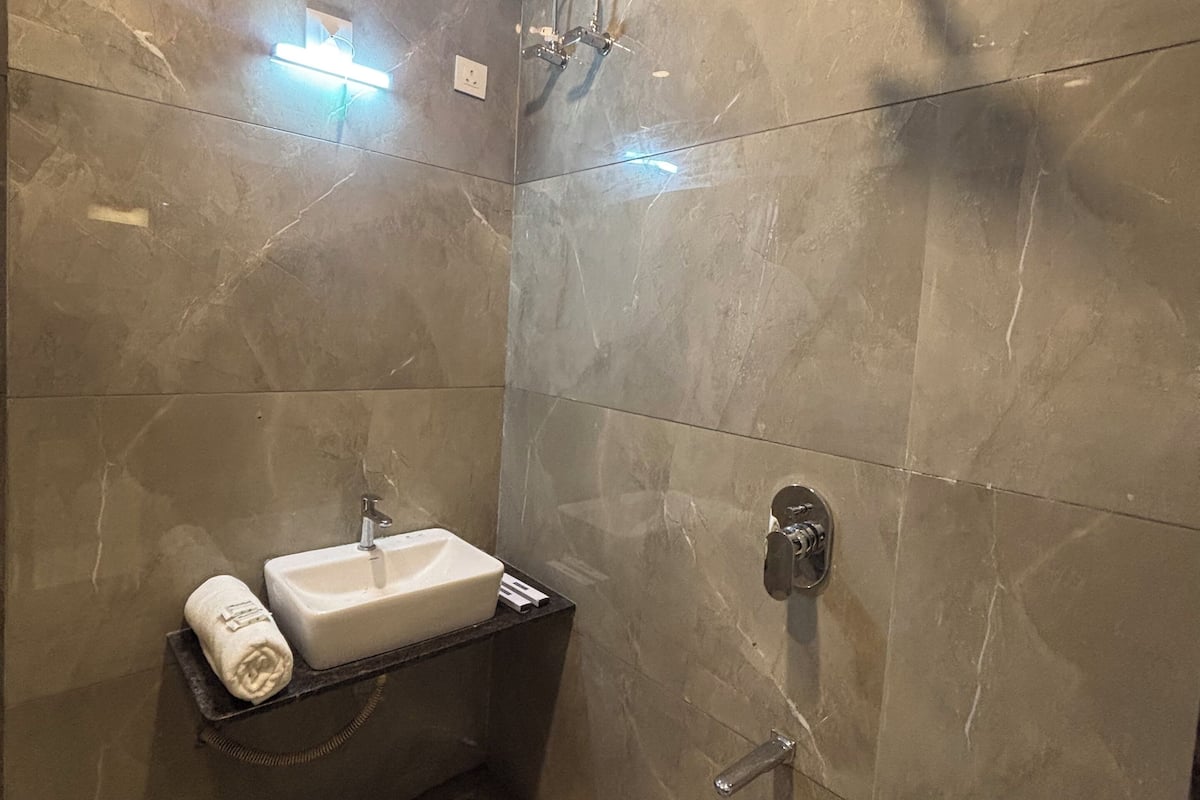 Un baño moderno con lavamanos, toalla y ducha.