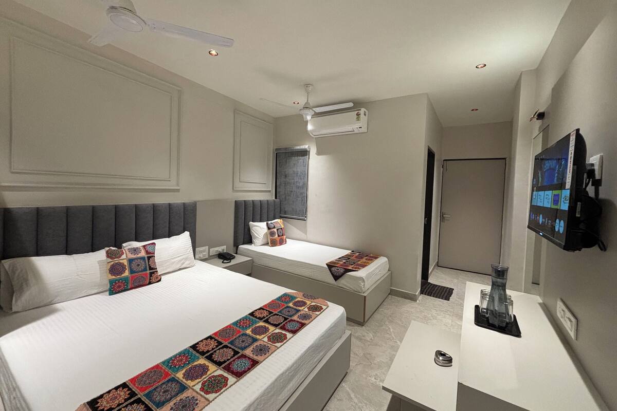 Una habitación de hotel con dos camas, un escritorio, un televisor y un ventilador de techo.