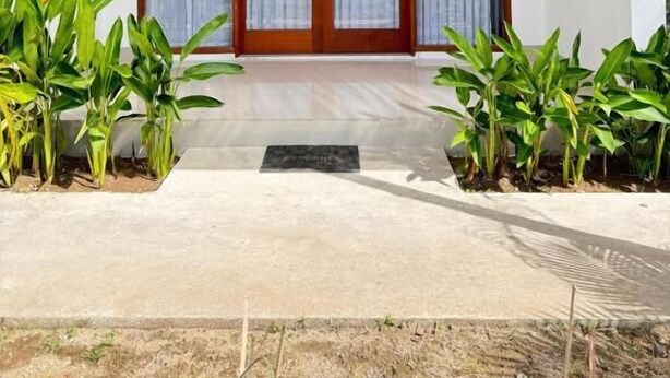 A modern house with a wooden pergola, a front door with glass panels, and potted plants on either side. - Turtle House 2 Lombok (Kuta)