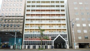 A multi-story hotel with a modern facade, featuring a prominent entrance with a glass canopy and a sign in a foreign language. - Hotel Stripe Sapporo (Sapporo)