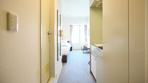 Een hotelgang met een bed, een bureau en een raam met gordijnen.