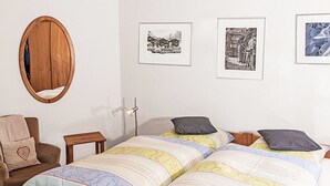 A bedroom with a bed, a chair, a mirror, and three framed pictures on the wall. - Apartment Laurin by Interhome (Zermatt)