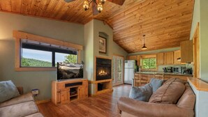 Un salon chaleureux avec une cheminée, un plafond en bois et un téléviseur.