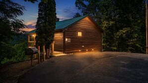 Une cabane en bois avec un toit en pente, une véranda et une allée gravillonnée.
