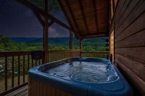 A hot tub on a wooden deck with a night sky view. - Charming Gatlinburg cabin for two with stunning mountain views. (Gatlinburg)