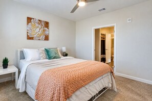 A bedroom with a bed, bedside tables, a ceiling fan, and a door leading to a bathroom. - Inviting 2 BR • Near IMG Academy • Pool  (Bradenton)