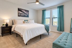 A bedroom with a bed, bedside table, lamp, and a cityscape painting. - Inviting 2 BR • Near IMG Academy • Pool  (Bradenton)