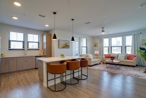 A modern kitchen with a central island, bar stools, and pendant lighting. - Inviting 2 BR • Near IMG Academy • Pool  (Bradenton)