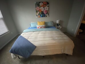 Ein Schlafzimmer mit einem Bett, einem Nachttisch, einer Lampe und einem Bild an der Wand.