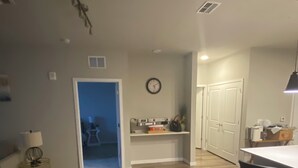 Amplia sala de estar con piso de madera, comedor con mesa y sillas, y cocina con un reloj en la pared.