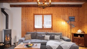 Un salon chaleureux avec une cheminée, des murs en bois, un canapé, une table basse et un meuble.