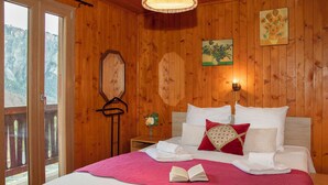 Une chambre à coucher aux murs lambrissés, avec un lit, des oreillers, une table de chevet ornée d’un vase et un luminaire suspendu.